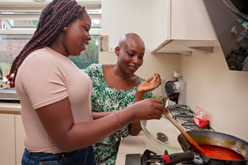 Mother and daughter (12-13) cooking in kitchen